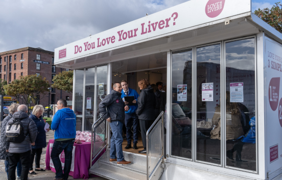 Our Love Your Liver roadshow events are very popular. Here a group of people stand in front of our mobile scanning unit, speaking to British Liver Trust staff and volunteers about liver health.